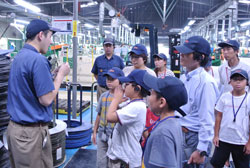 自動車に使われるネジの製造工程の説明を聞きながら、工場内を見学する子どもたち。（トープラ大阪工場）